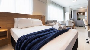A modern hotel room with a large bed, a desk, a chair, and a bathroom visible in the background. - Botanik With Coworking, Pet Place, and Skyview By Carpediem (Recife)