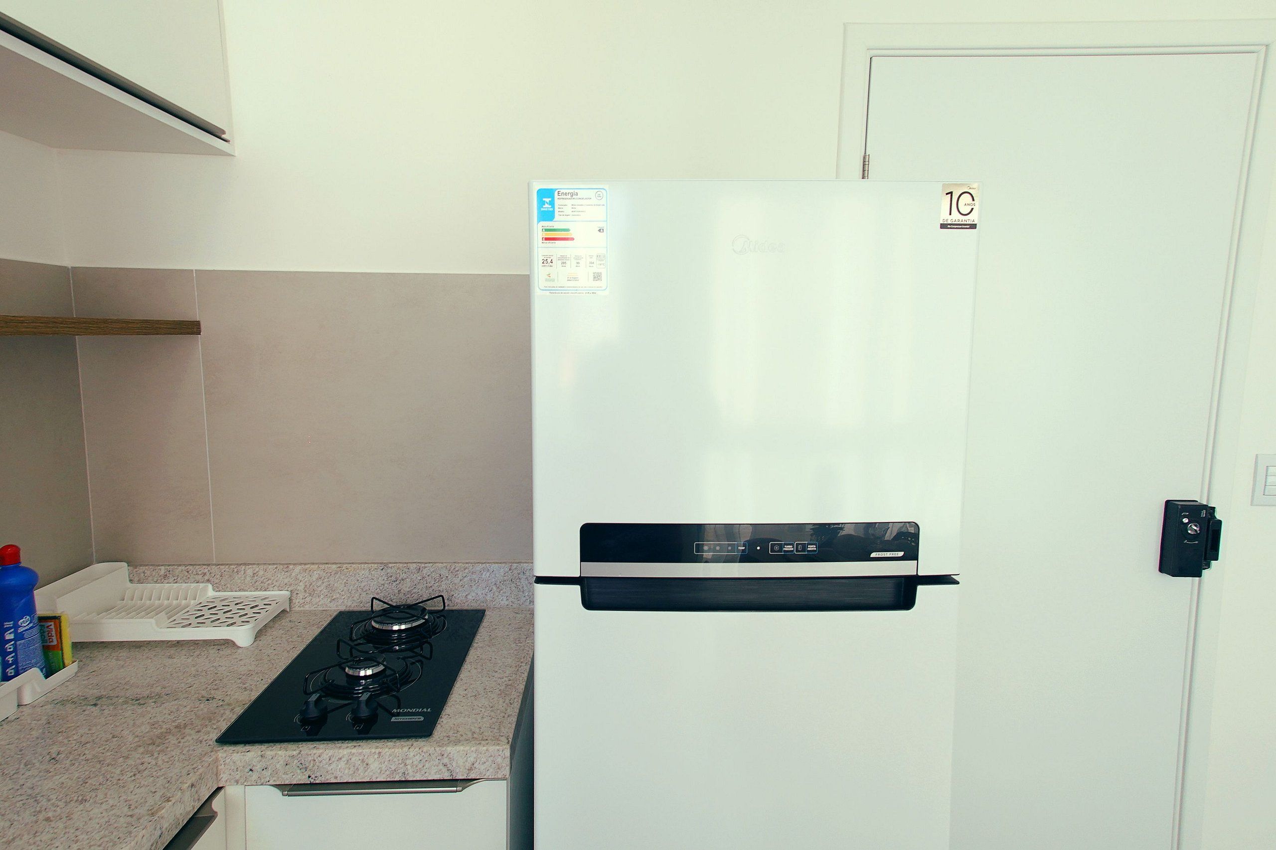Una cocina con un refrigerador blanco, una estufa a gas y una puerta blanca.