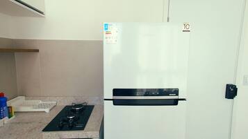 Una cocina con un refrigerador blanco, una estufa a gas y una puerta blanca.