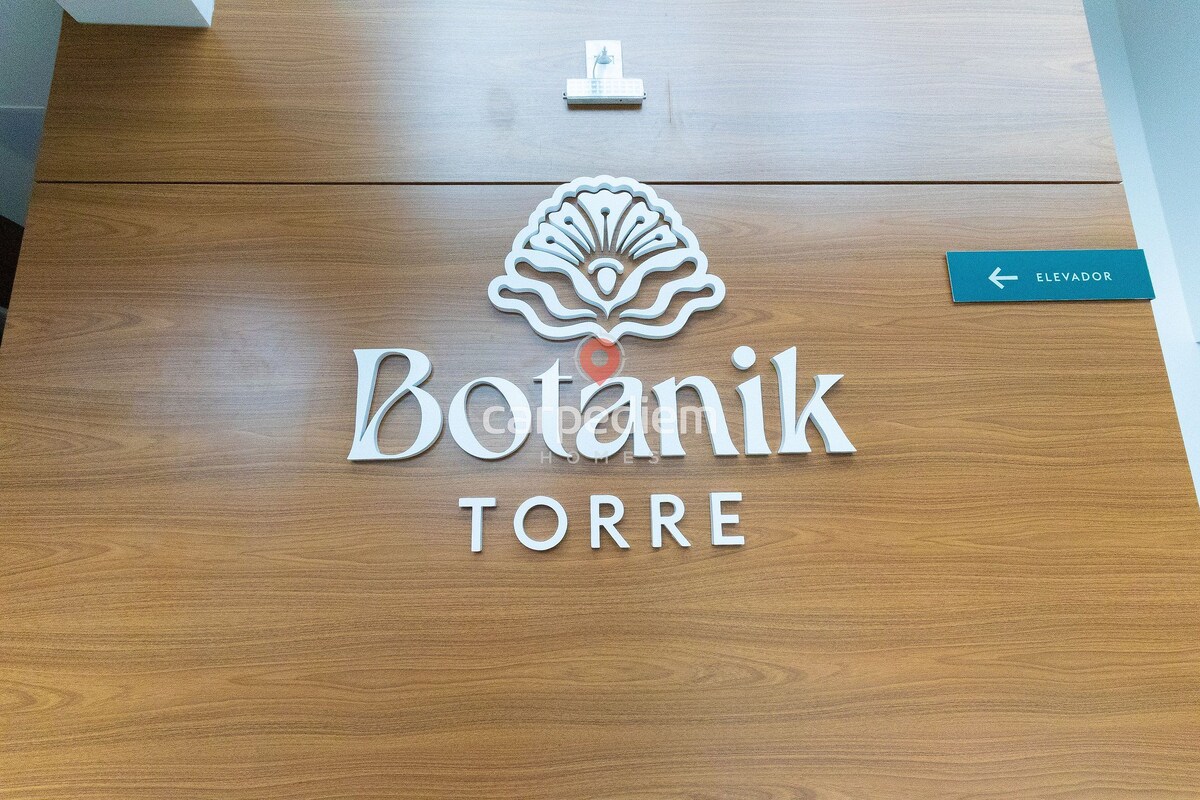 Puinen vastaanottotiski, jossa on kyltti, jossa lukee ”Botanik TORRE”, ja nuoli, joka osoittaa hissiin.