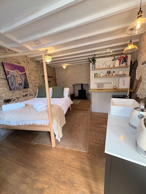 A cozy bedroom with a bed, a wooden desk, and a stone wall. - Poppy's Studio Collection - Harbour Townhouse and The Hideaway (Mevagissey)
