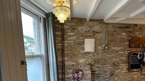 Una mesa redonda con un centro de mesa floral, una pared de piedra y una araña.