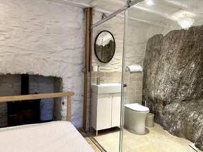 A bathroom with a stone wall, a round mirror, a sink, and a toilet. - Poppy's Studio Collection - Harbour Townhouse and The Hideaway (Mevagissey)