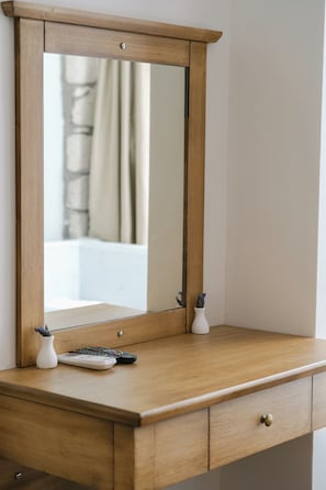Un aparador de madera con un espejo, un florero y un control remoto.