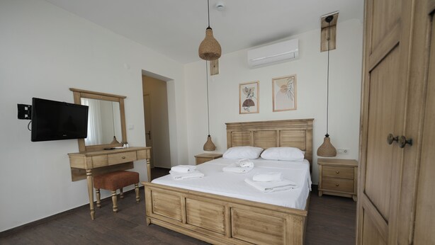 Un dormitorio con una cama de madera, un escritorio, un televisor y un armario.