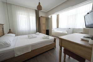 Una habitación de hotel con cama, escritorio, televisor y armario.
