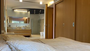 Ein Schlafzimmer mit zwei Betten, ein Badezimmer mit Waschbecken und Spiegel sowie ein begehbarer Kleiderschrank.