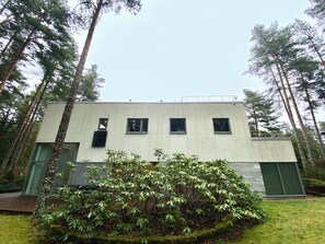 Un edificio moderno con techo plano, ventanas rectangulares y puerta verde.