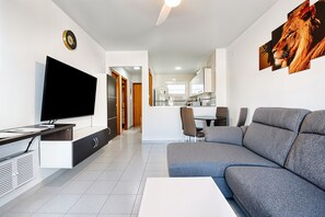 A modern living room with a flat-screen TV, sofa, and dining area.