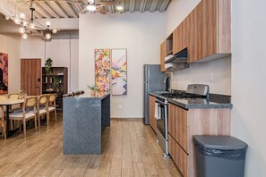 A modern kitchen with wooden cabinets, a central island, stainless steel appliances, and a dining area with wooden furniture. - Luxury 3BR in Roma Norte – Walk to Top Spots (Ciudad de México)