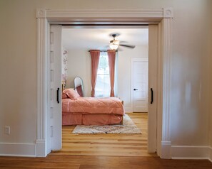Ein Schlafzimmer mit einem Bett, einem Deckenventilator und einem Fenster mit Vorhängen.