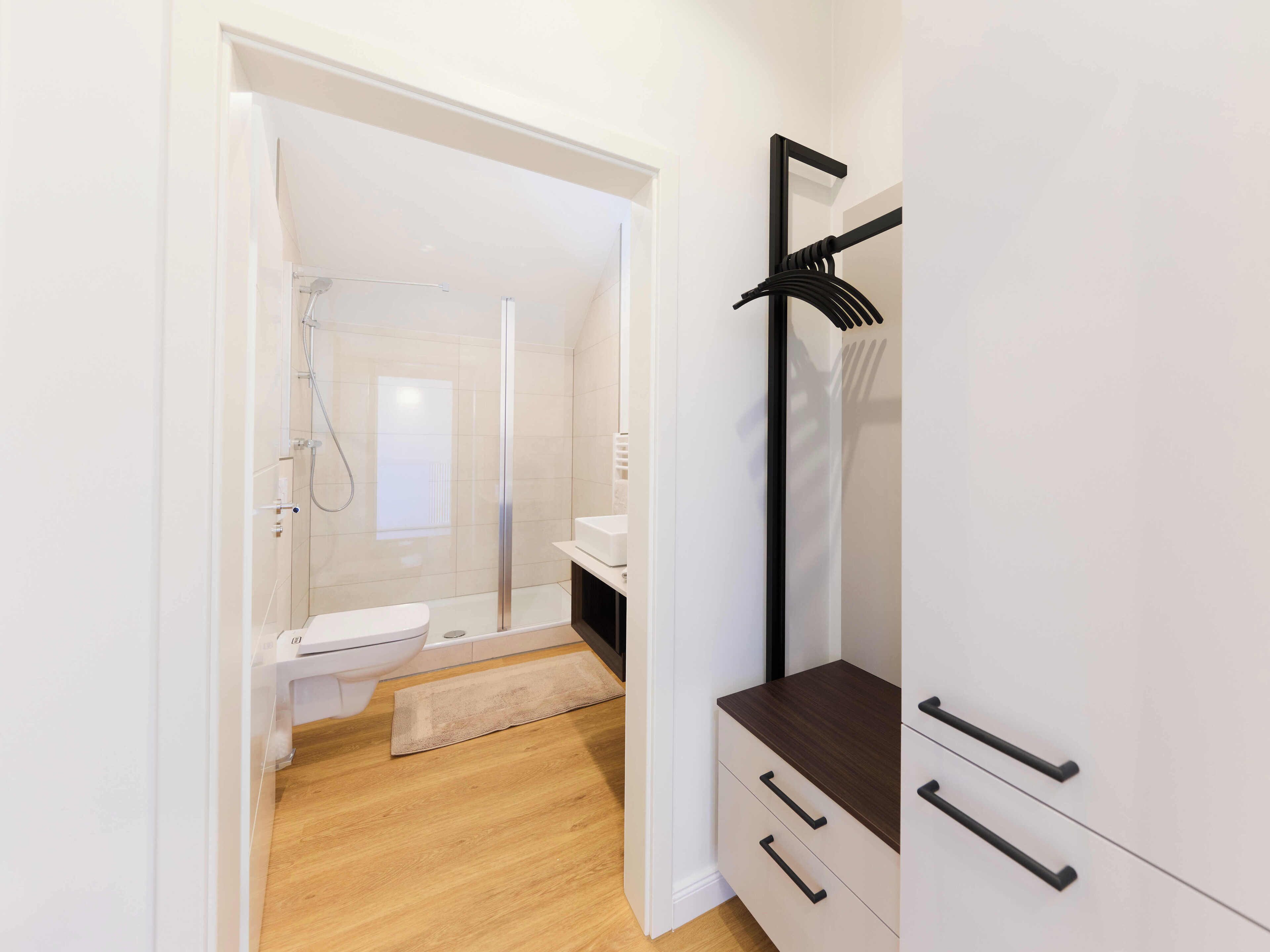Ein modernes Badezimmer mit Dusche, Toilette und Holzboden.