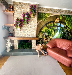 Una sala de estar con pared de piedra, chimenea, sofá y una estatua de ciervo.