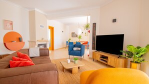 A modern living room with a sofa, a coffee table, a TV, and a dining area in the background. - Casa Cardhu in Carvoeiro (Lagoa)