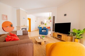 Ein modernes Wohnzimmer mit einer Couch, einem Couchtisch, einem Fernseher und einem Essbereich im Hintergrund.