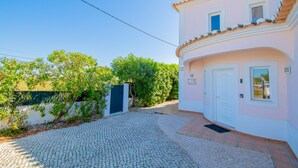 A two-story building with a cobblestone driveway, a white door, and a small window. - Casa Cardhu in Carvoeiro (Lagoa)