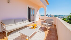 A balcony with a sofa, chairs, a table, and a view of the city. - Casa Cardhu in Carvoeiro (Lagoa)