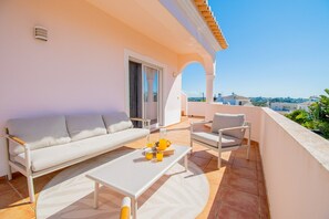 A balcony with a sofa, chairs, a table, and a view of the city. - Casa Cardhu in Carvoeiro (Lagoa)