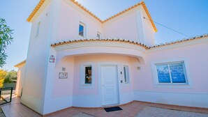 A two-story building with a white facade, a balcony, and a door with a window. - Casa Cardhu in Carvoeiro (Lagoa)