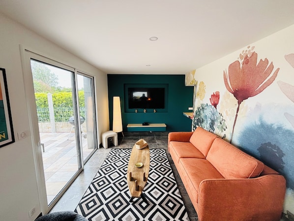 Ein modernes Wohnzimmer mit einer Couch, einem Fernseher und einem gemusterten Teppich.