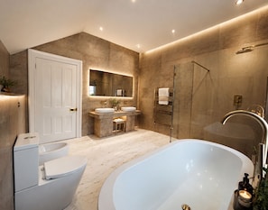 Une salle de bain moderne avec une baignoire, deux lavabos, une douche et un grand miroir.