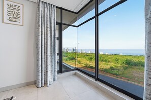 Ein Zimmer mit einem großen Fenster, einem Vorhang und einem gerahmten Bild an der Wand.
