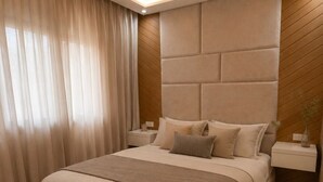 Un dormitorio moderno con una cama grande, una mesita de noche y un panel en la pared.