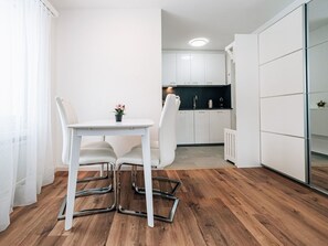 Eine moderne Küche mit weißen Schränken, einer schwarzen Arbeitsplatte und einem kleinen Tisch mit Stühlen.