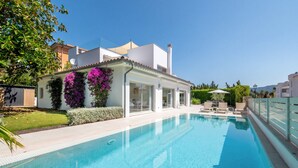 Uma casa moderna com piscina, jardim e vista para o mar.