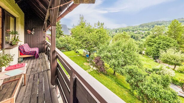 A wooden balcony with a view of a lush green landscape.