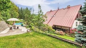 A residential property with a swimming pool, outdoor seating, and a well-maintained garden.