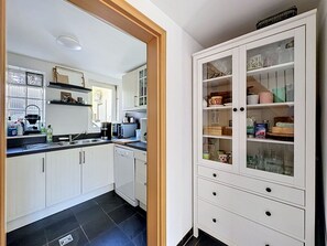 A kitchen with white cabinets, a black tiled floor, and a white cabinet with glass doors containing kitchenware.