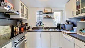 Une cuisine moderne avec des meubles blancs, une cuisinière en acier inoxydable et un lave-vaisselle.