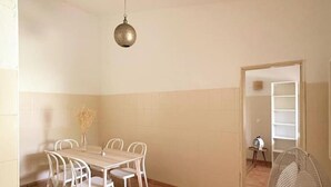 Un espace repas comprenant une table et des chaises, un luminaire suspendu et une porte donnant sur une autre pièce.