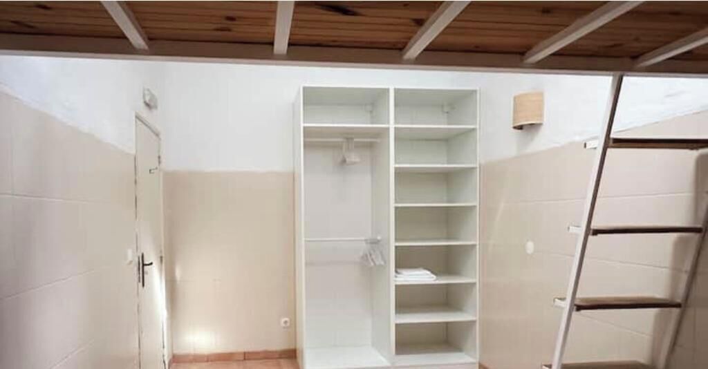A room with a built-in closet, a door, and a wooden ceiling.