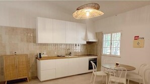 Una cocina con alacenas blancas, un mueble de madera, un fregadero, una estufa y una mesa de comedor con sillas.