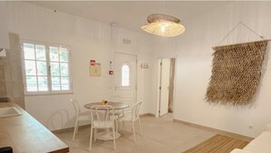 Una habitación con una mesa de comedor, sillas, una lámpara colgante, un tapiz de pared tejido y una puerta.