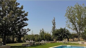 Piscina con sillas de descanso, rodeada de árboles y un cielo despejado.