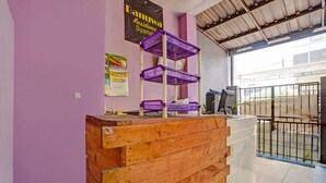 A reception desk with a wooden finish, purple baskets on top, and a banner reading 'Banuwa Residence Syariah'. - Inviting Standard DBL Stay W/wifi Parking Access (Surabaya)