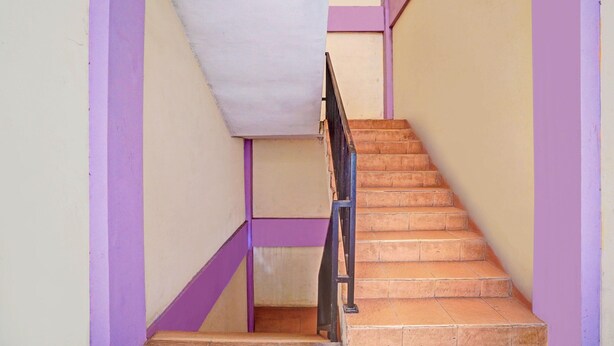 A staircase with a handrail, wooden steps, and walls painted in purple and beige. - Inviting Standard DBL Stay W/wifi Parking Access (Surabaya)