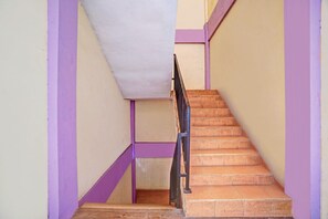 A staircase with a handrail, wooden steps, and walls painted in purple and beige. - Inviting Standard DBL Stay W/wifi Parking Access (Surabaya)