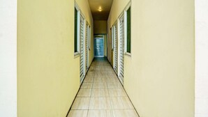 A narrow hallway with doors on both sides, leading to a room with a view. - Inviting Standard DBL Stay W/wifi Parking Access (Surabaya)