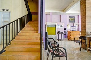 Un escalier mène à un espace d’accueil où un panneau indique qu’il est réservé au personnel. On y trouve un comptoir d’accueil et un tableau d’affichage où sont affichées des informations.