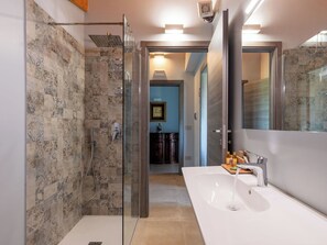 Un bagno moderno con cabina doccia in vetro, uno specchio grande e un lavandino bianco.