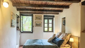 Une chambre à coucher avec un lit, une table de chevet, une lampe, une fenêtre et une porte.
