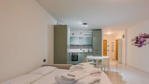 Une chambre d’hôtel moderne équipée d’un lit, d’un petit coin cuisine et d’une table à manger.