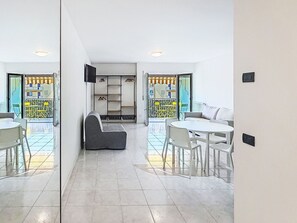 A modern interior with a sofa, dining table, chairs, a TV, and a wardrobe. - Lovely apartment for 3 guests with WIFI, TV, patio, pets allowed and panoramic view (Riva Del Garda)