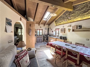 A cozy interior with a dining table, wooden furniture, a kitchen area, and a staircase leading to an upper level.