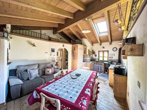A cozy interior with a dining table, sofa, and kitchen area.