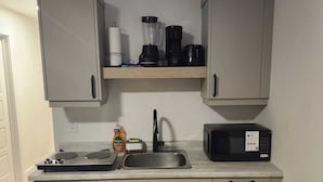 Una cucina compatta con forno a microonde, fornello, lavandino e mobili.